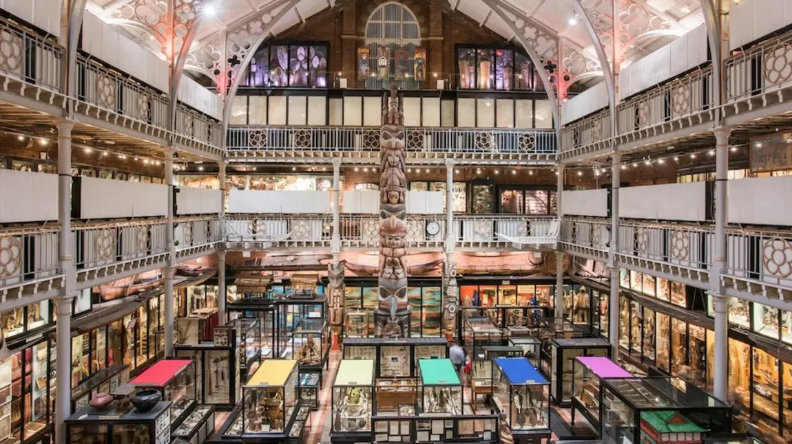 The inside of the PItt Rivers Museum, a large open indoor space with exhibition cases