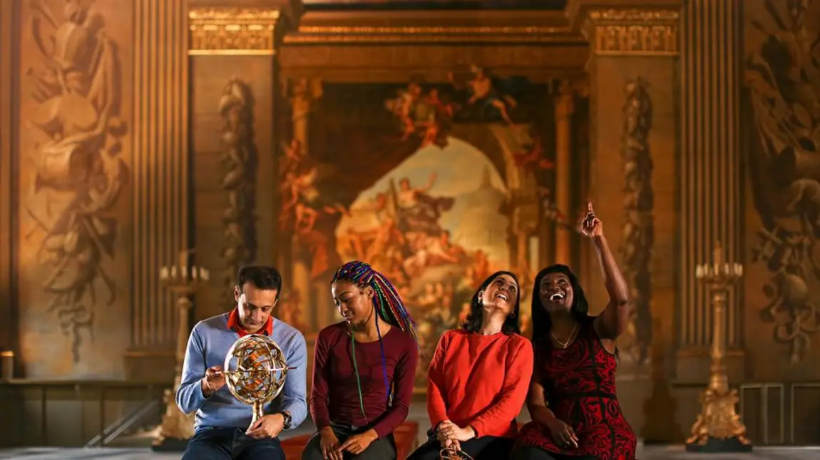 People sitting on a bench in a museum, pointing and looking at an exhibition