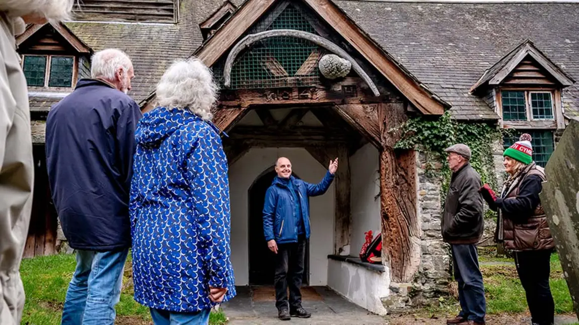 An outdoor scene of a person welcoming a group of people to a church