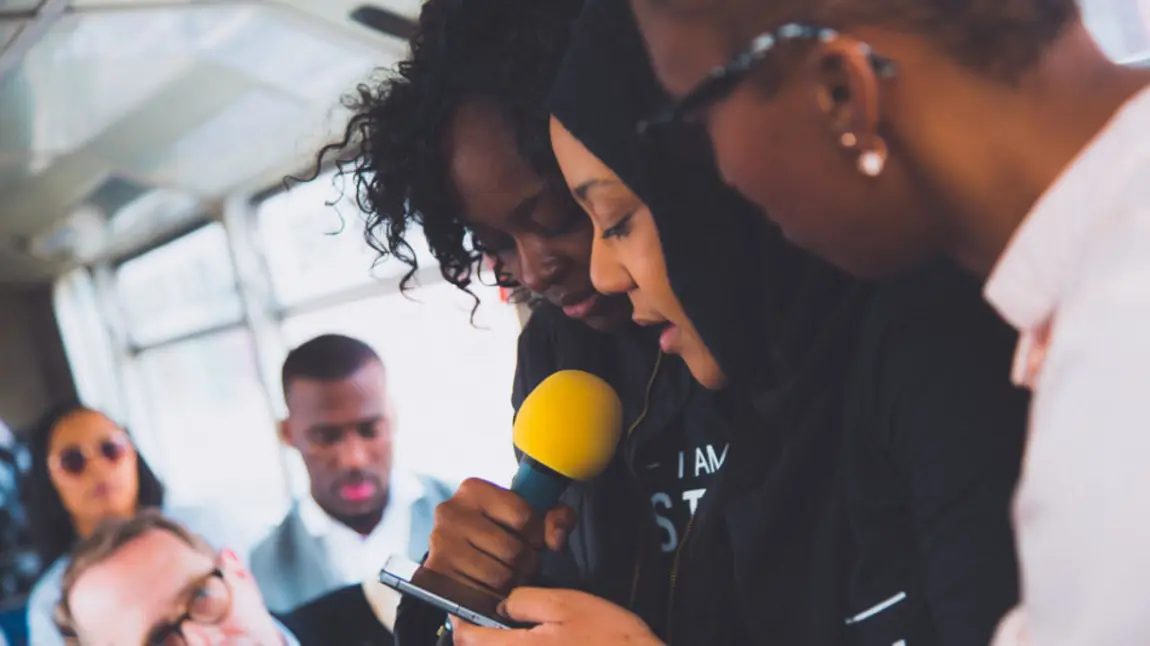 Young people reading poetry around a microphone
