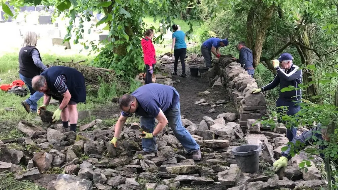 Volunteers work on rebuilding dry stone walls at St Nicholas Church, 