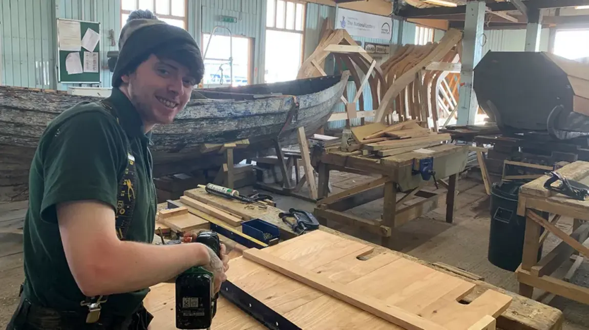 Person using a drill in a boatyard workshop