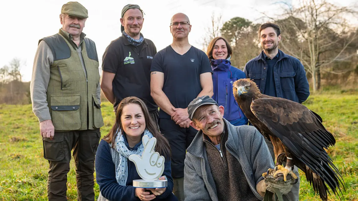 Golden eagles soar in Scotland’s National Lottery Award winning project. Group of people holding award and an eagle