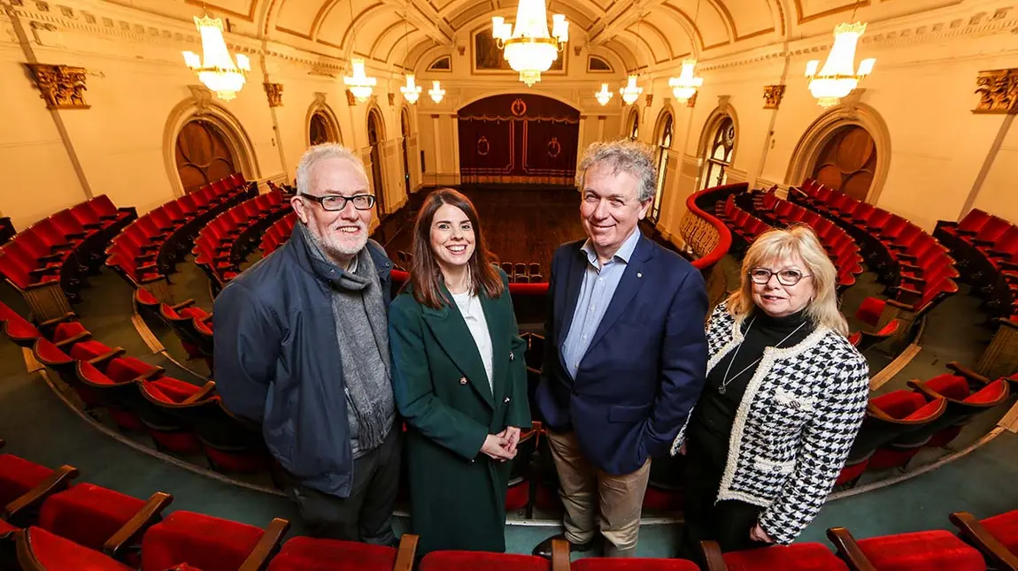 Four people stand in a grand hall