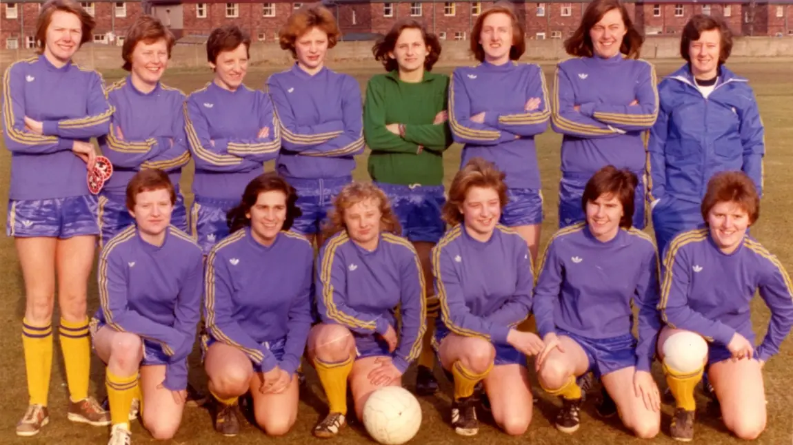 Women's football team face the camera in two rows - one standing behind, one kneeling in front.