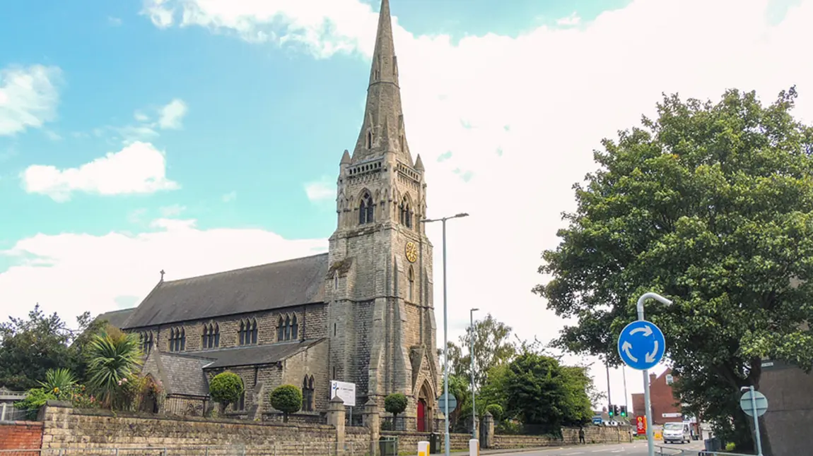 A stone church with a spire, in a town