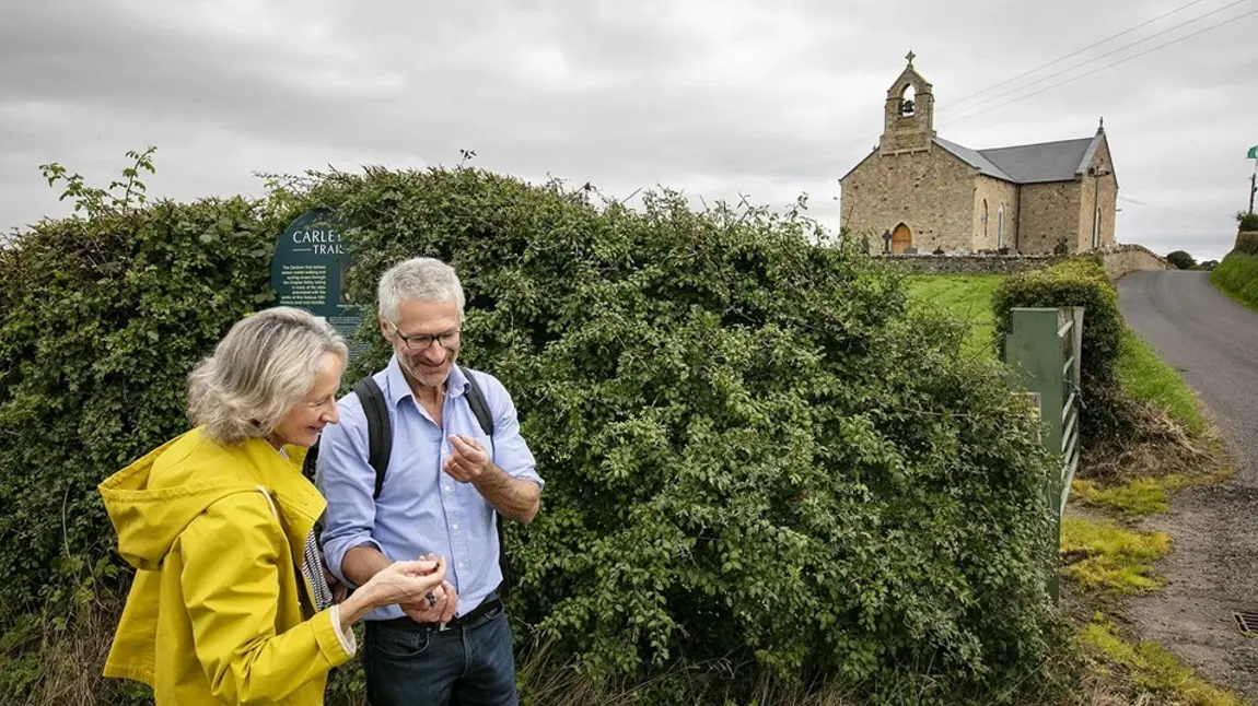 Two people standing with a church on a hill in the background