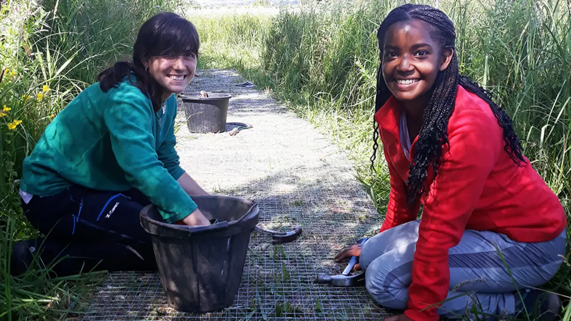 Two women working on a path at a wildlife reserve