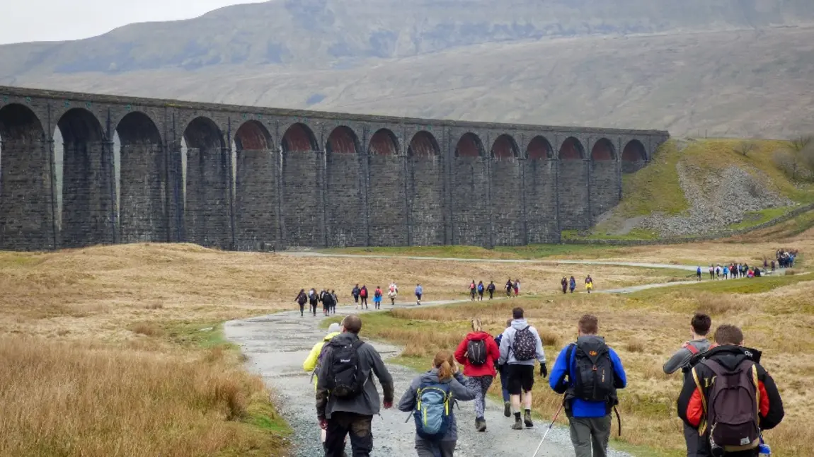 People walking along a country path by a viaduct in Yorkshire