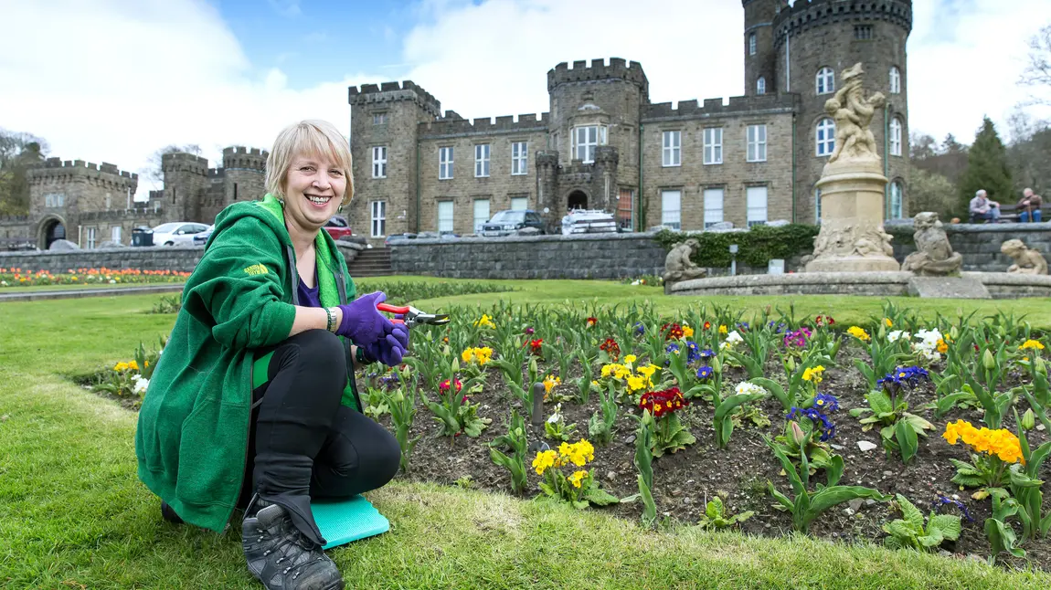 Woman crouching in grounds of a castle