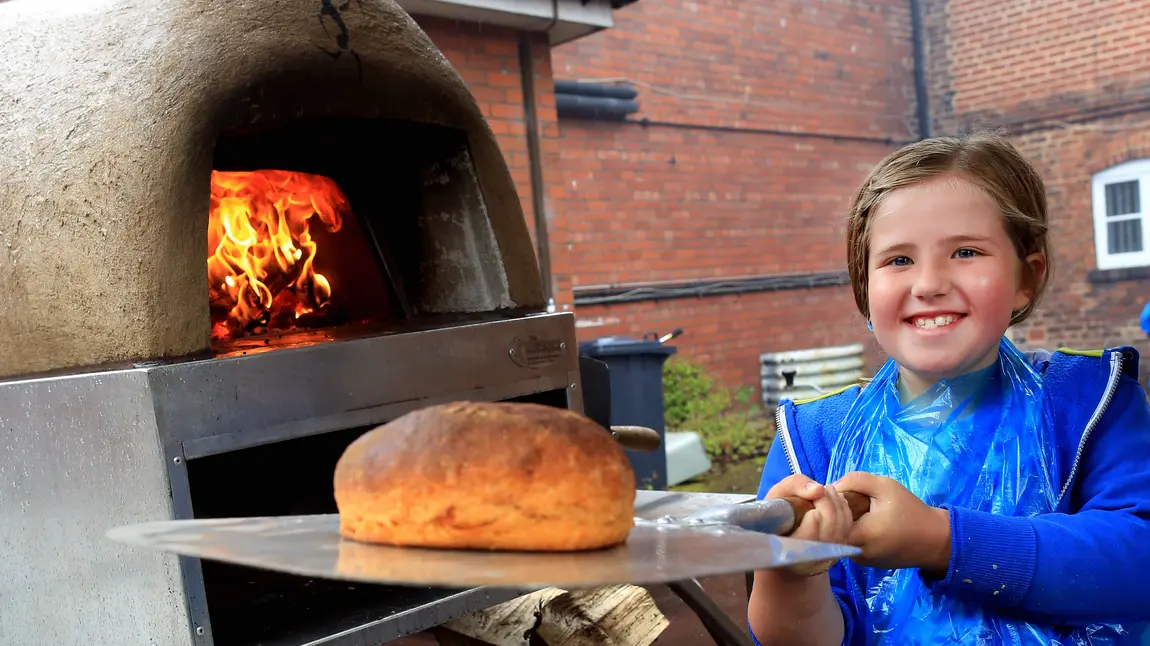 Girl puts loaf in oven