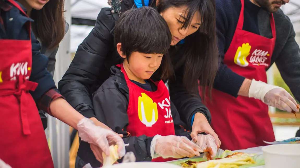 A child being shown how to make kimchi