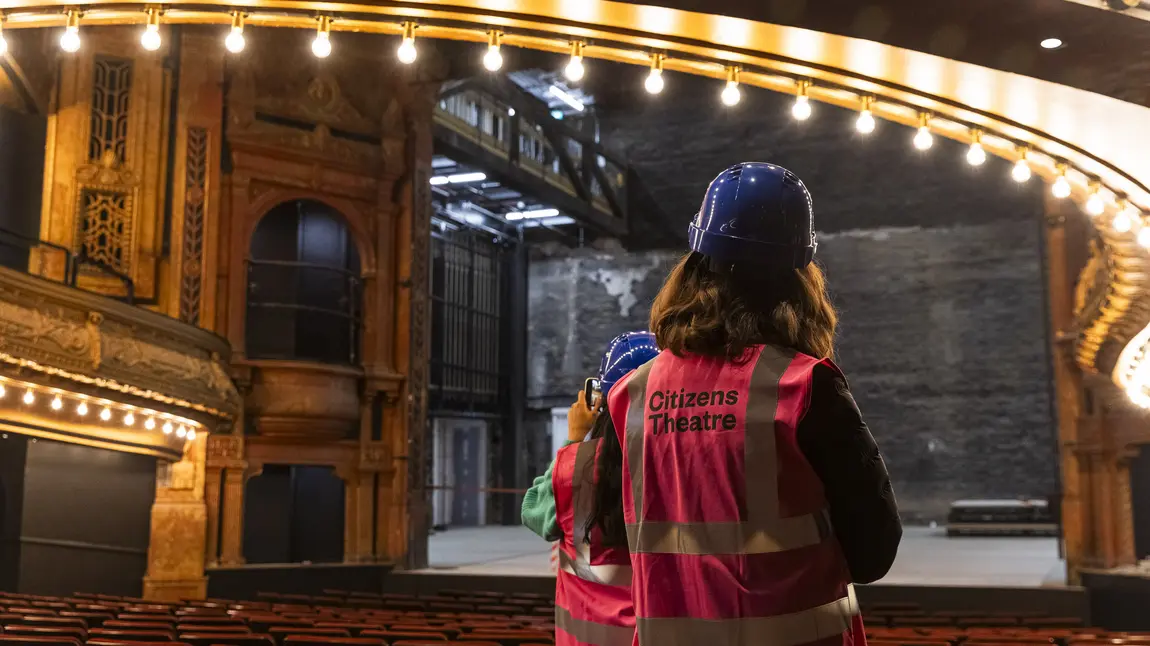 Two people in high vis jackets and hard hats explore the restored auditorium.