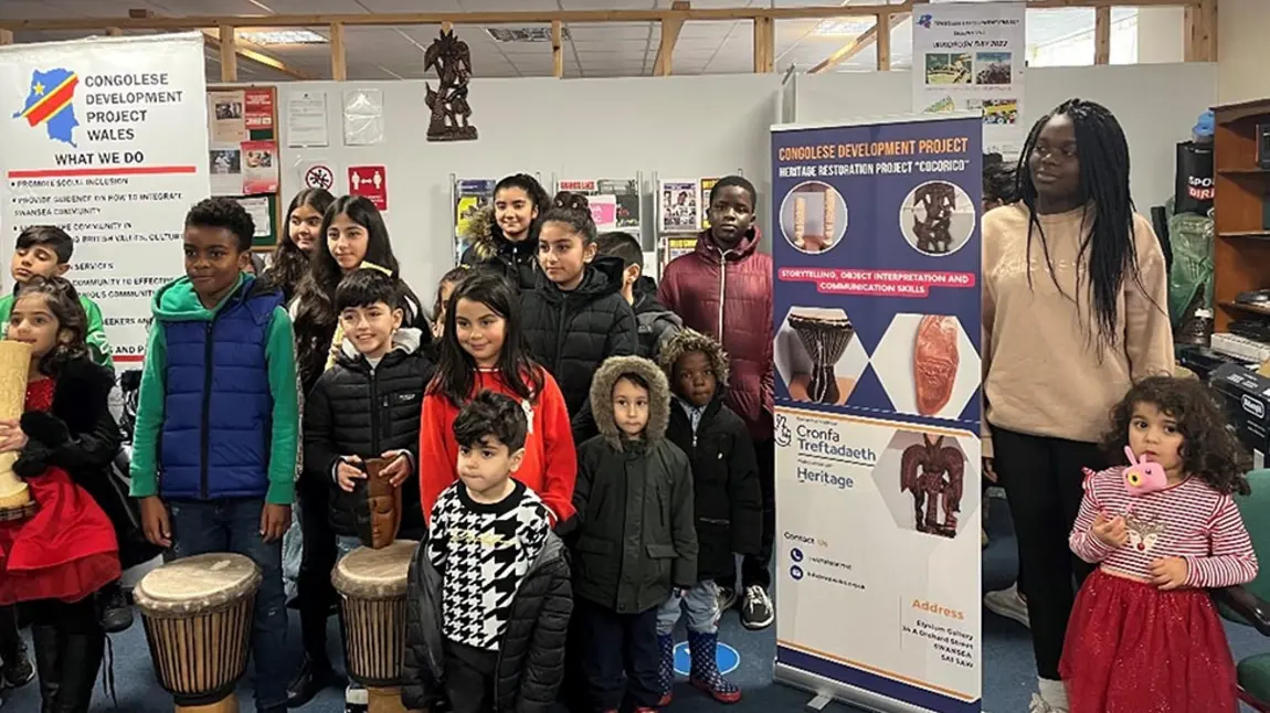 A group of children posing for a photograph, some holding family objects