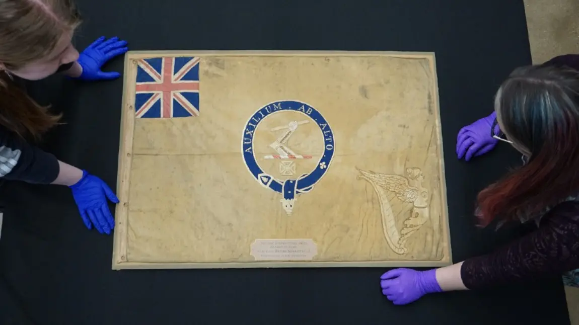 Conservators from the National Museum of the Royal Navy with the polar Kellett sledge flag