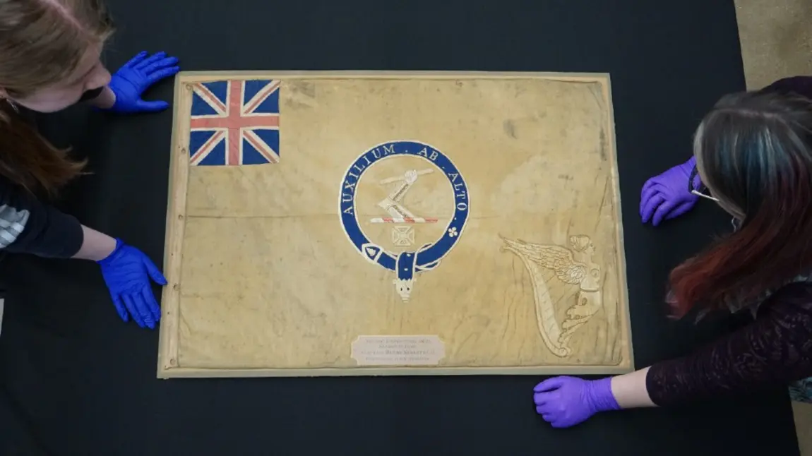 Conservators from the National Museum of the Royal Navy with the polar Kellett sledge flag Conservators from the National Museum of the Royal Navy with the polar Kellett sledge flag