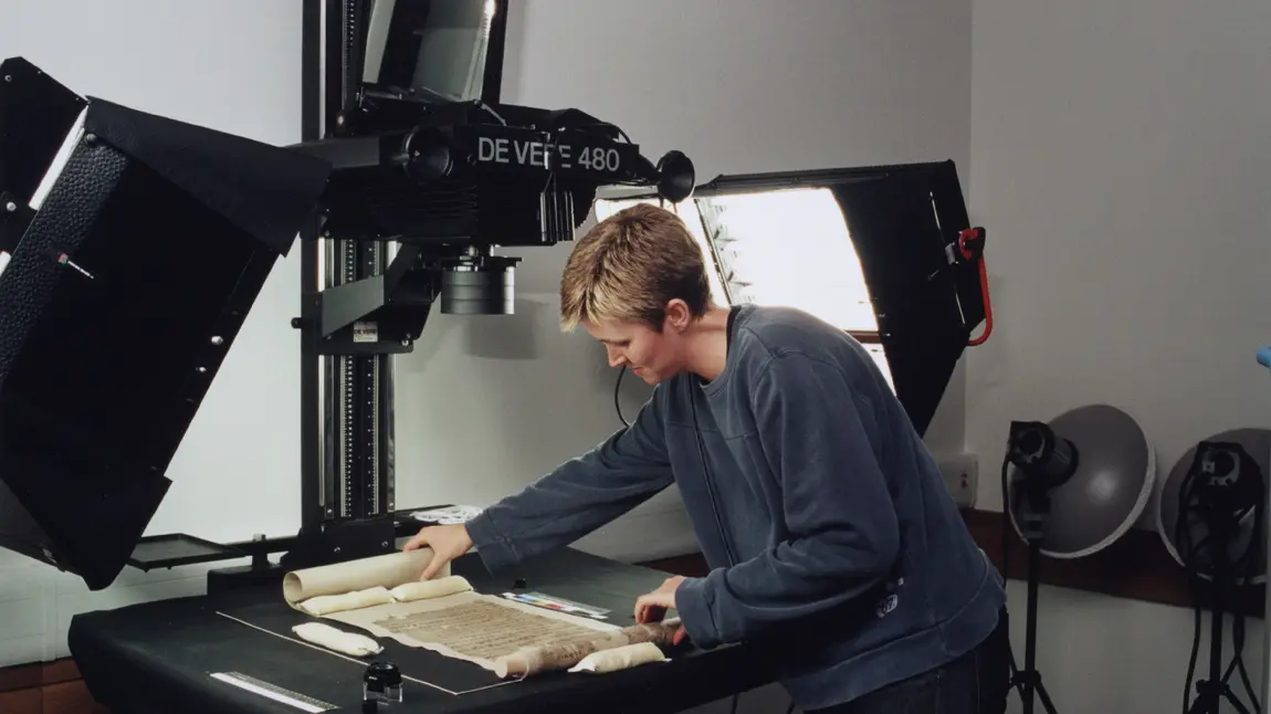 A woman placing a manuscript under a professional digitisation device