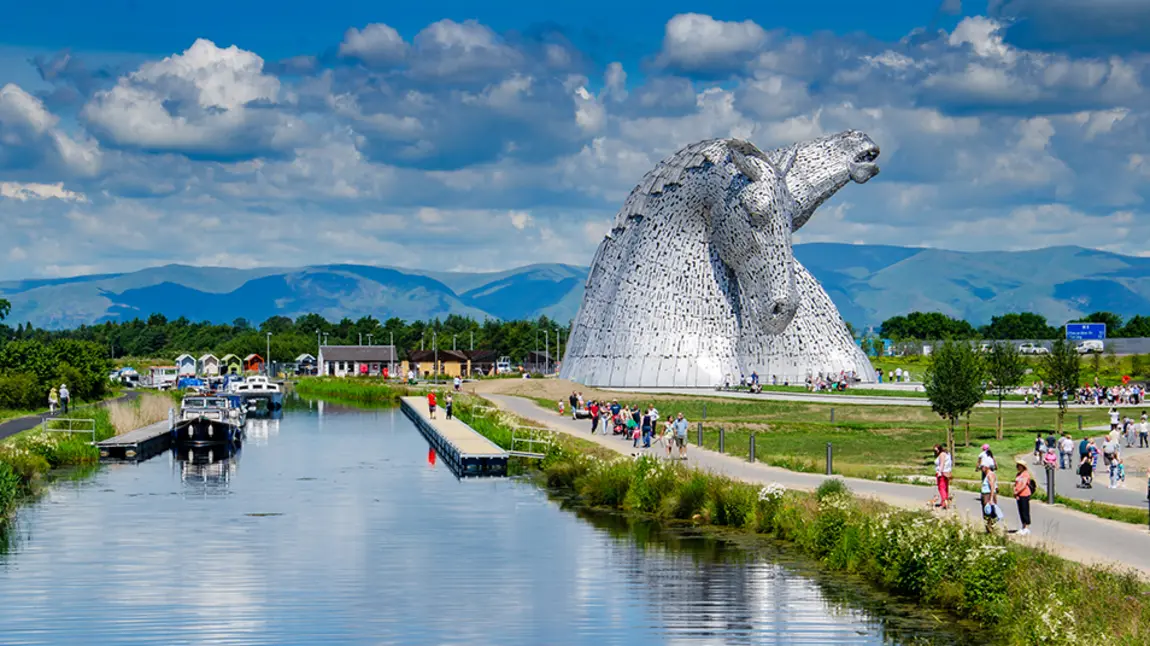 The Falkirk Kelpie sculptures, with boats on the canal and people walking along the paths