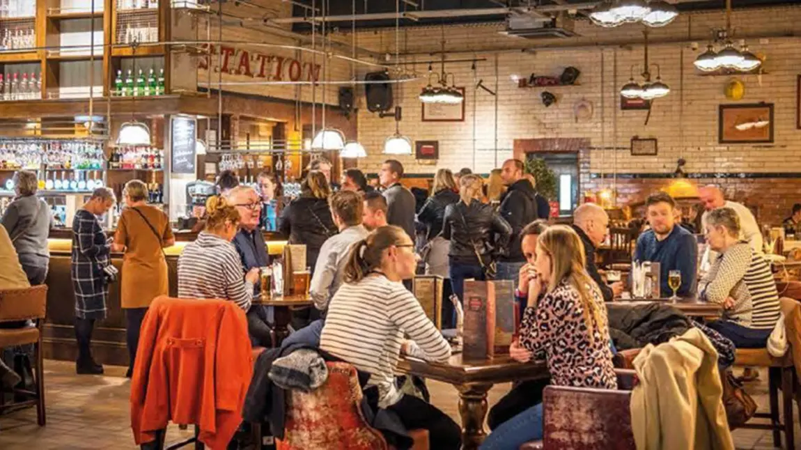 A well lit, crowded bar with people sitting at tables