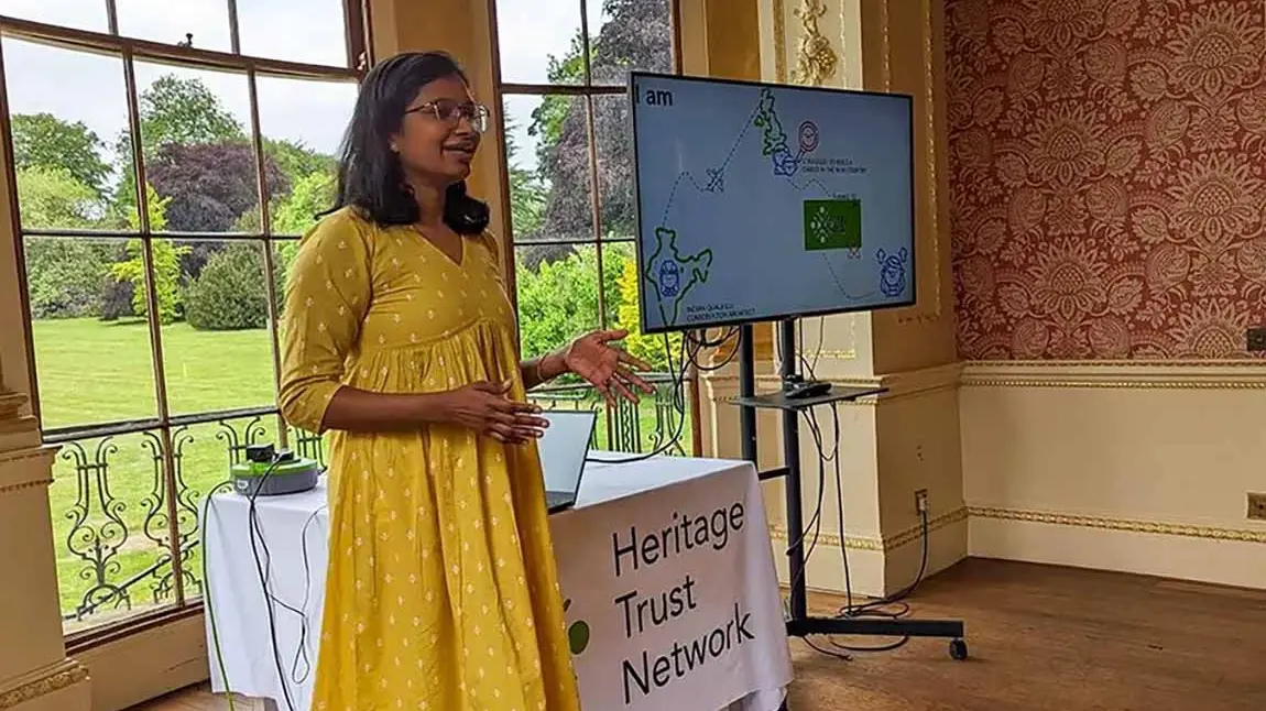 Gopika Jayasree stands beside a digital screen and gives a talk