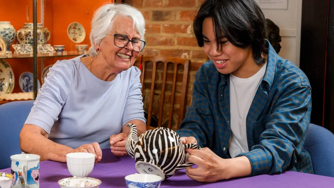 An older woman and a young adult man looking at ceramics