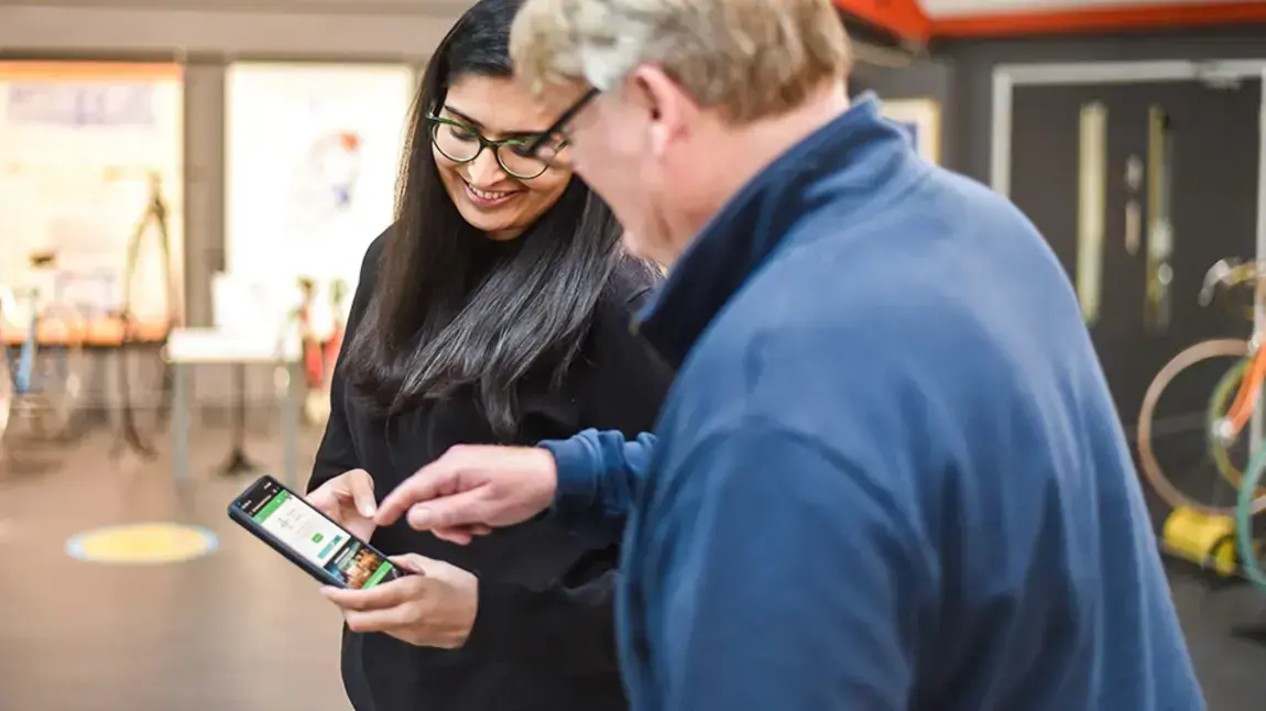 A young women showing an older man how to access an app on a mobile phone