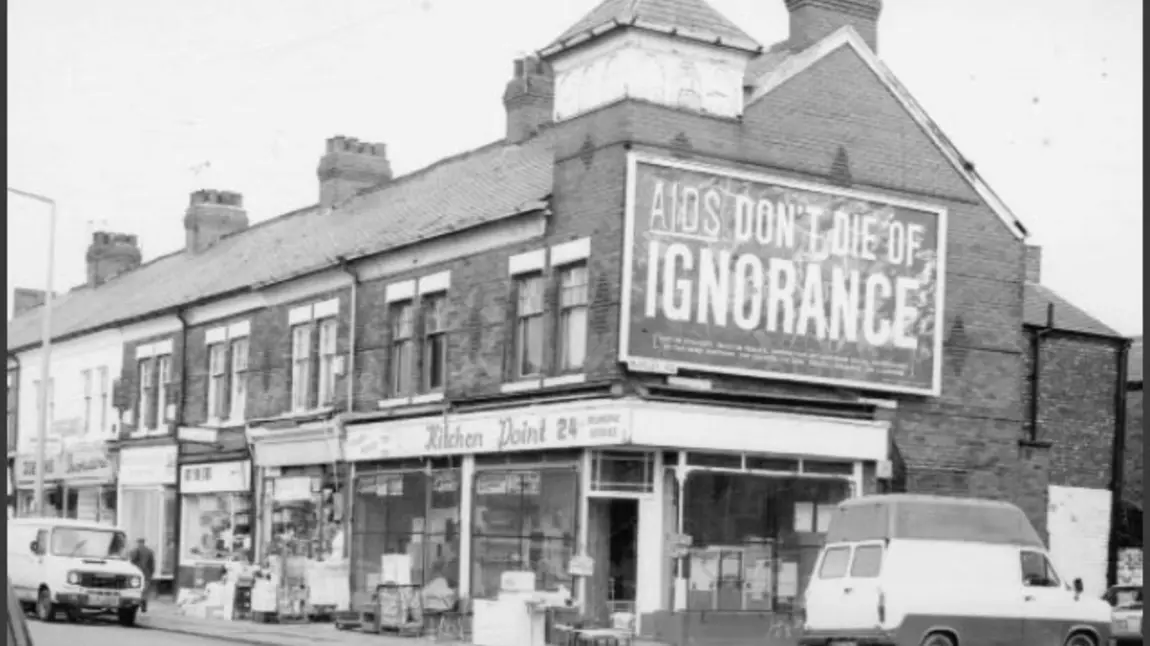 Old photo showing large billboard with the words "AIDS: don't die of ignorance"