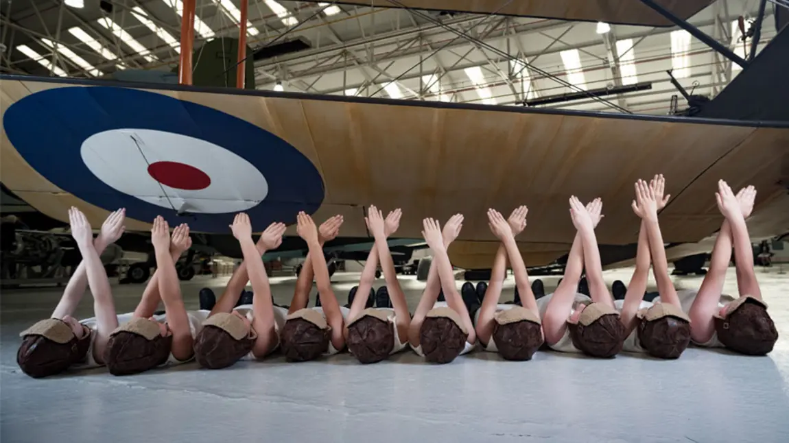 Children performing under the wing of an old RAF aeroplane 