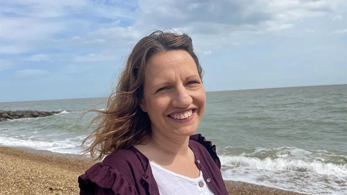 Emma Fernandes-Lopes A woman with light brown hair and white skin stands on a beach