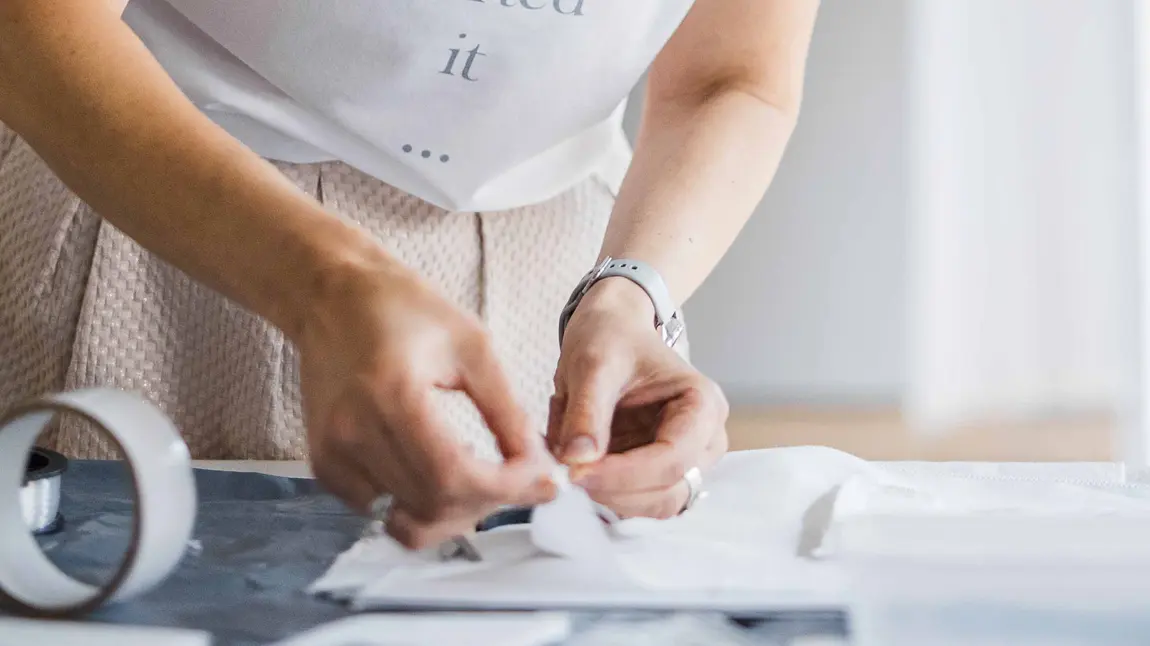 A person's hands handling a folded piece of white linen on a flat surface