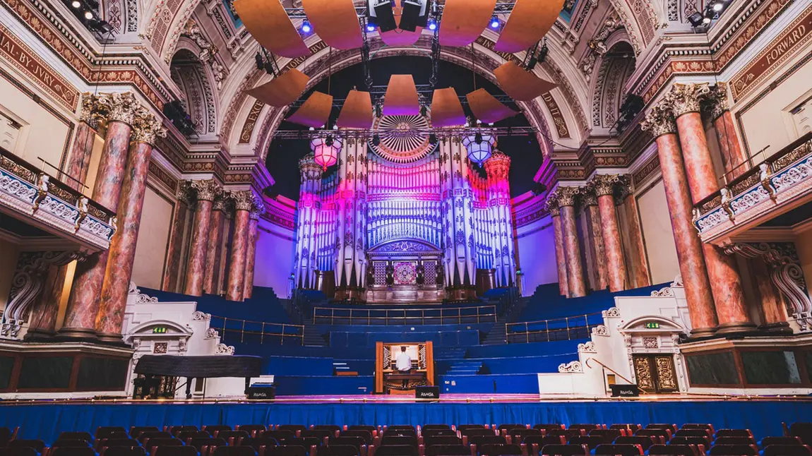The interior of Leeds Town Hall with someone playing the organ on stage.