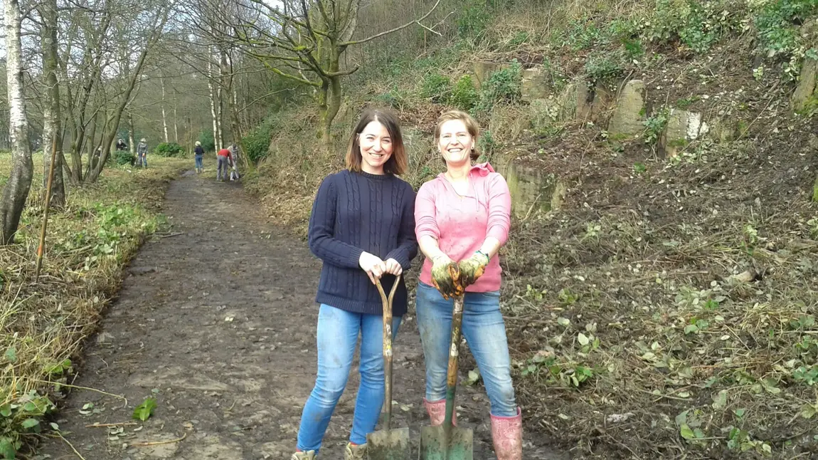 Two volunteers using shovels to help clear a footpath