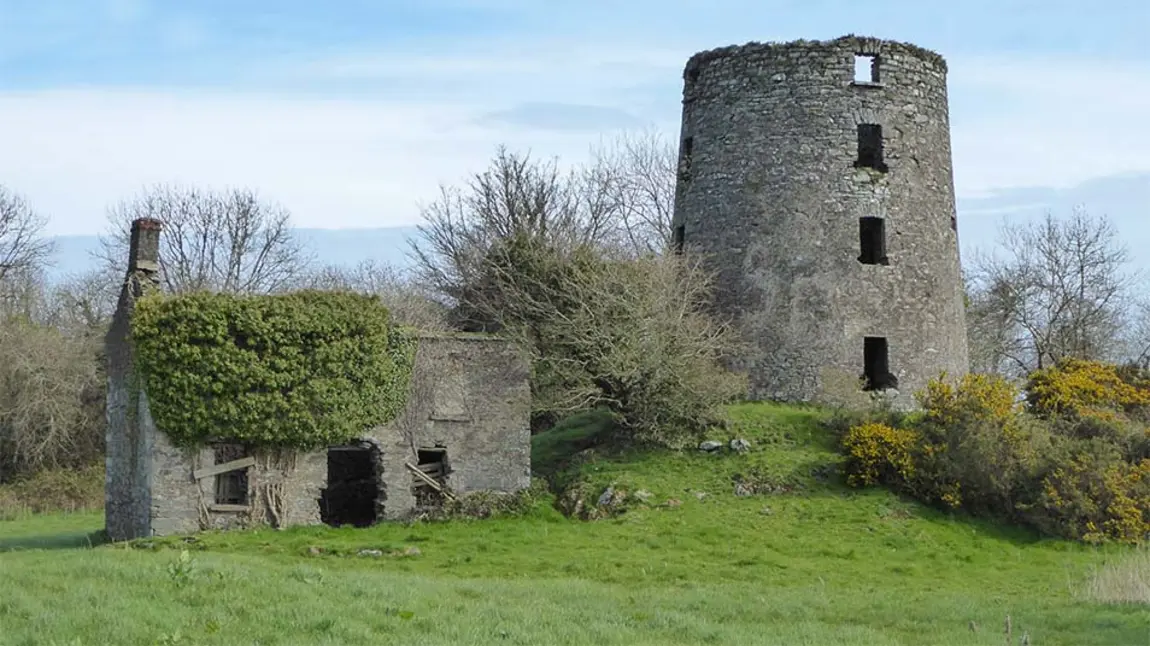 a ruined stone windmill building in the countryside