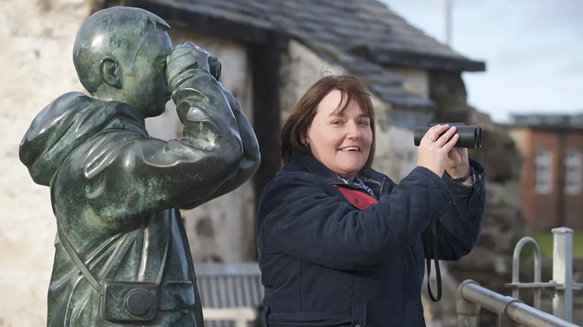 Woman with binoculars next to statue