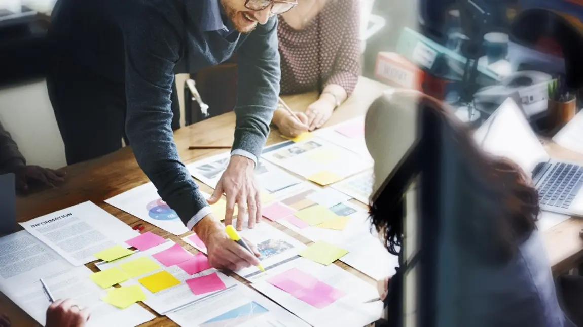 People working on an office desk with bright sticky notes