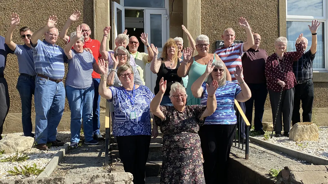 A group of older people waving