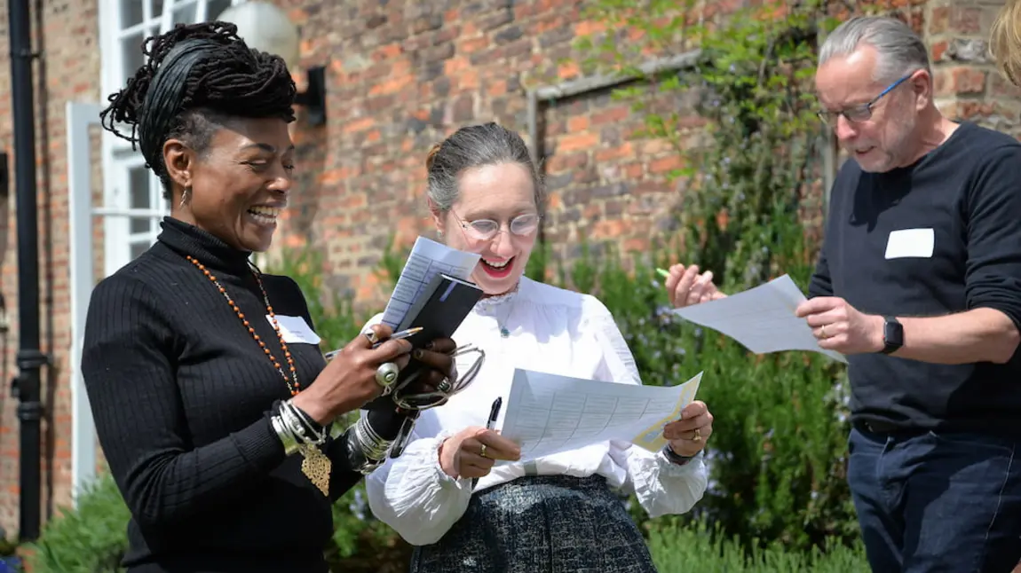 Three people are looking at worksheets and smiling.