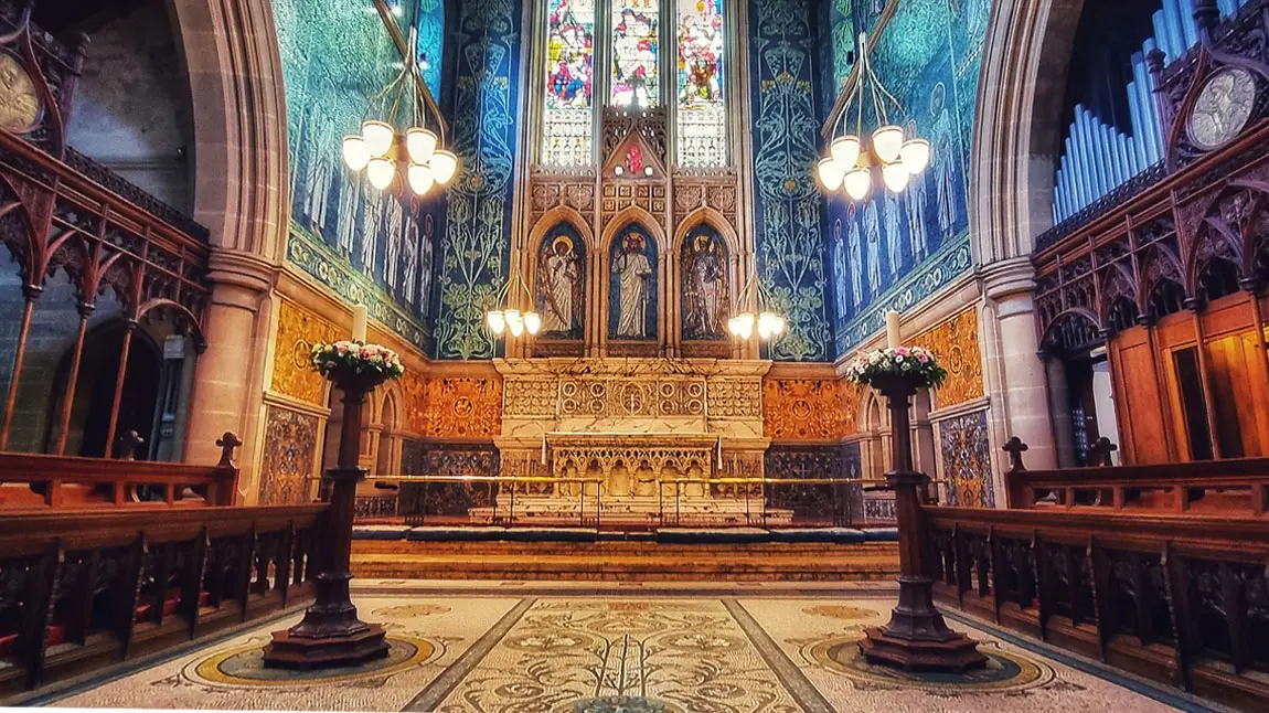 An interior view of a church altar with stained glass windows in the background