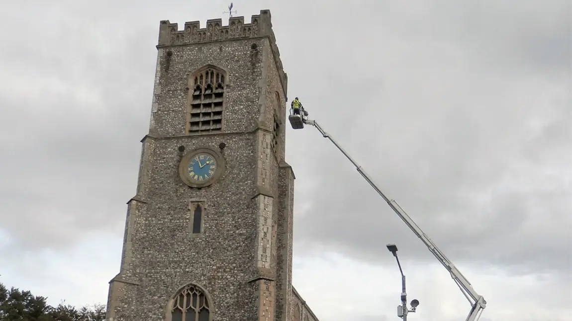 The tower of St Nicholas with a person on a crane assessing the tower roof