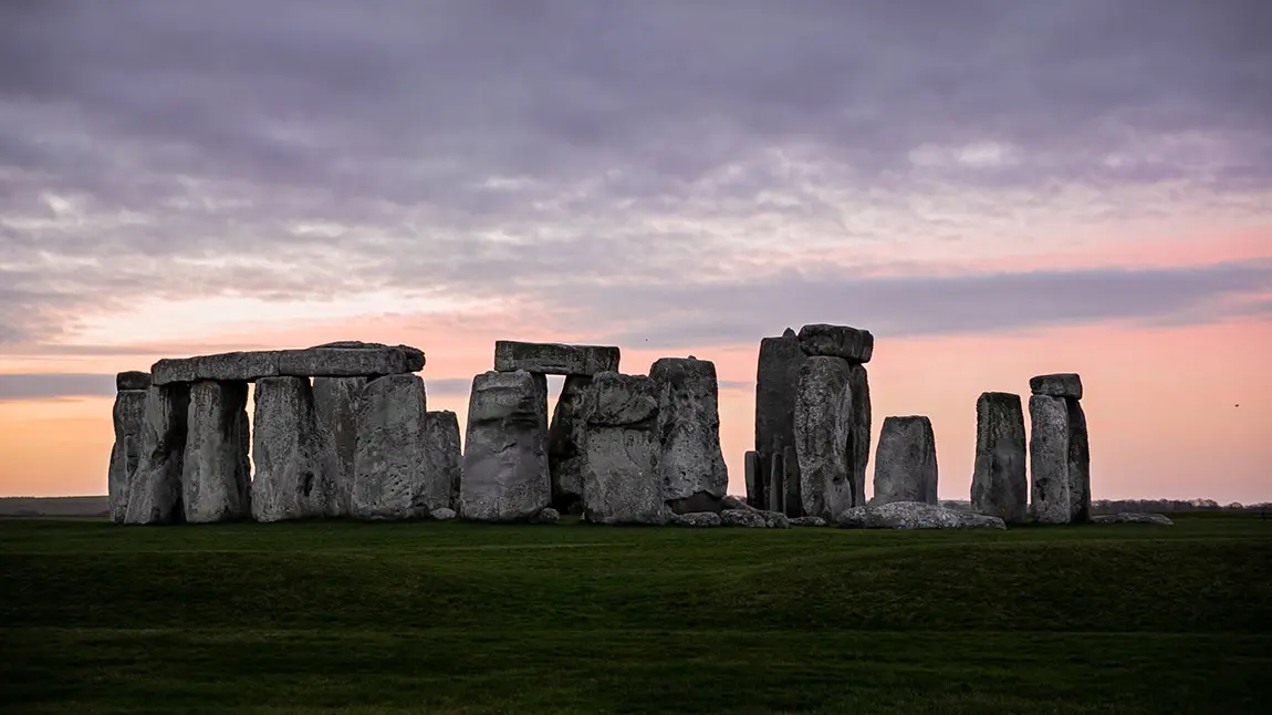 Stonehenge circle of large stones against a pink and purple sunset