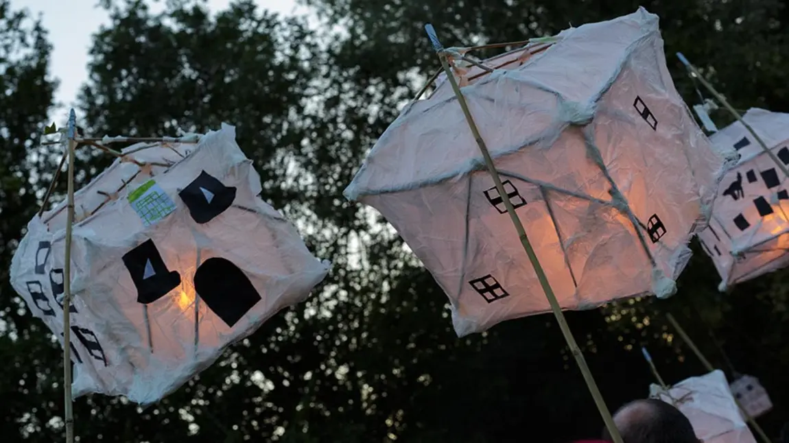Two paper lanterns in the shape of houses in an outdoor parade