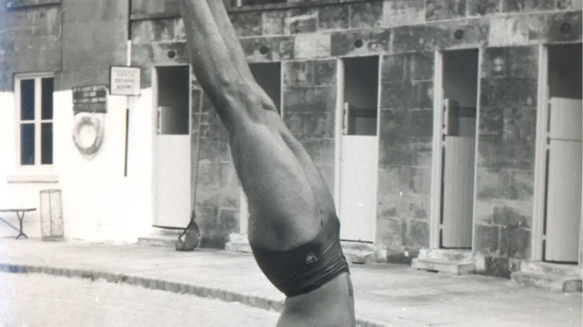 Man doing a handstand by a swimming pool