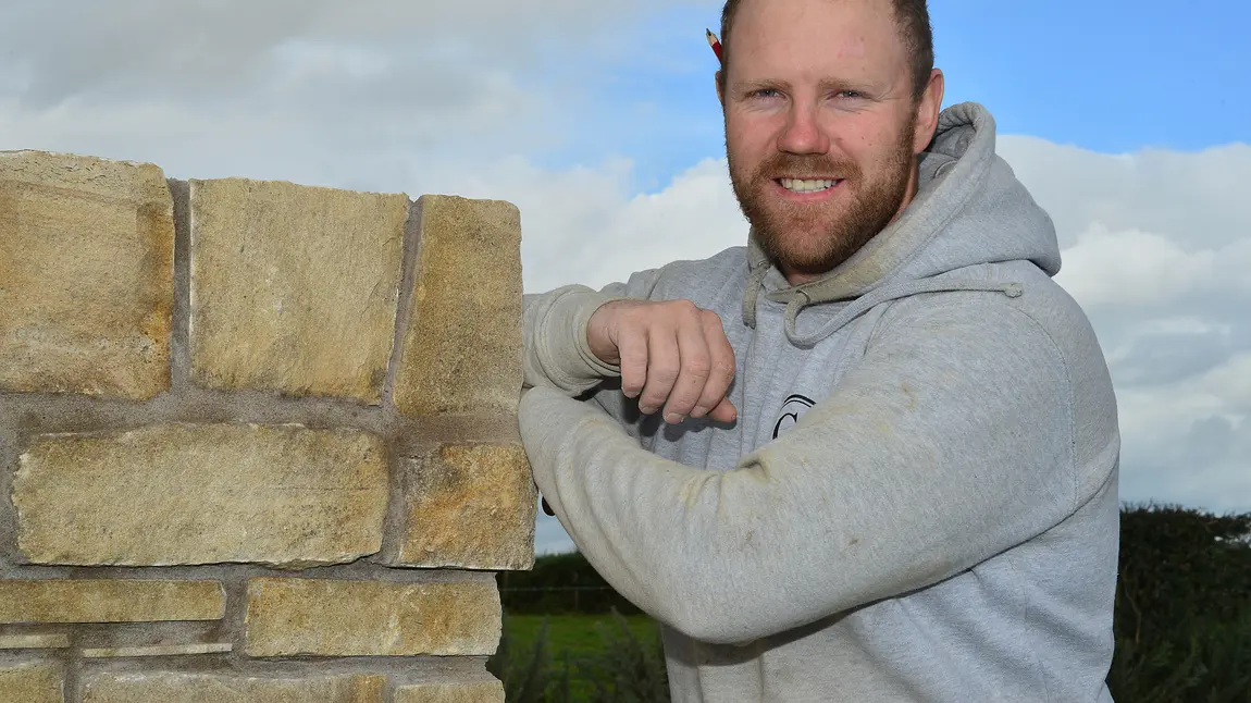 Conor Scullion posing next to some stonework