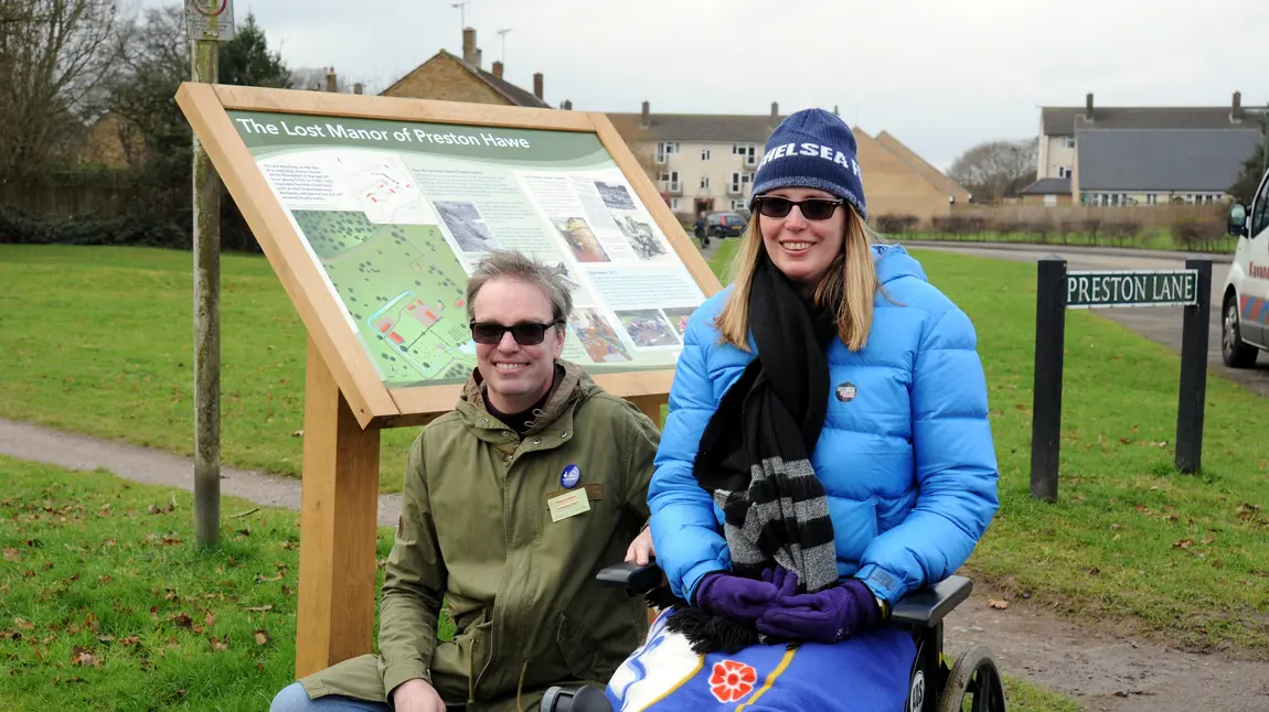 Volunteers Wayne and Antoinette by an information board