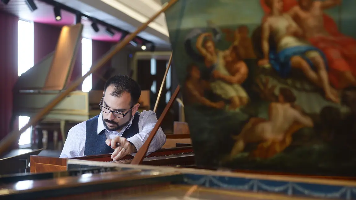 Conservator Jonathan Santa Maria Bouquet tuning a harpsichord in the museum 