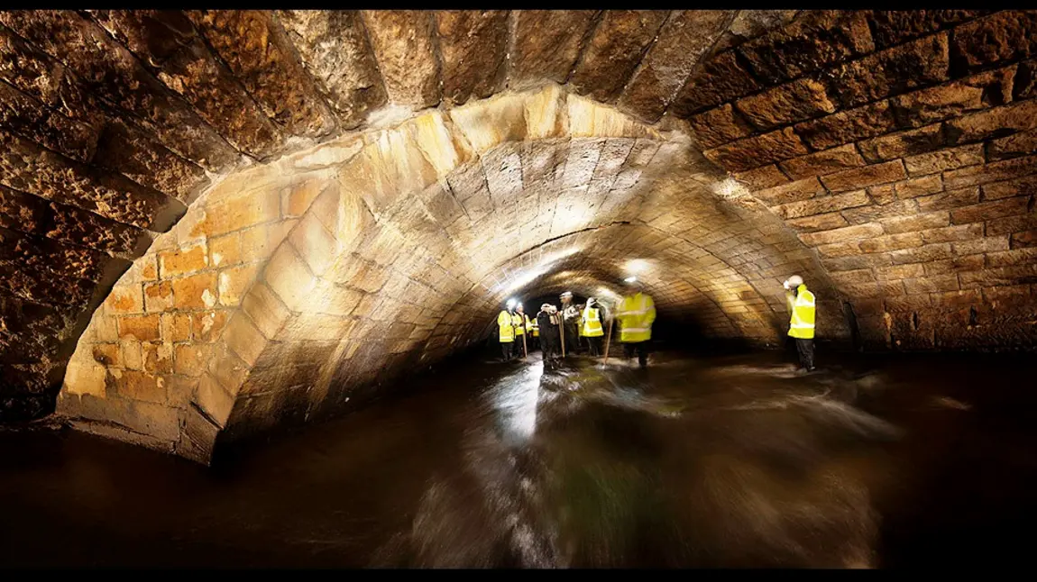 People inspecting the River Roch's medieval bridge