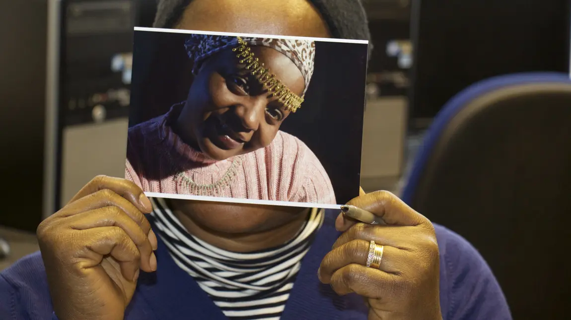 A woman holds a photograph over her face