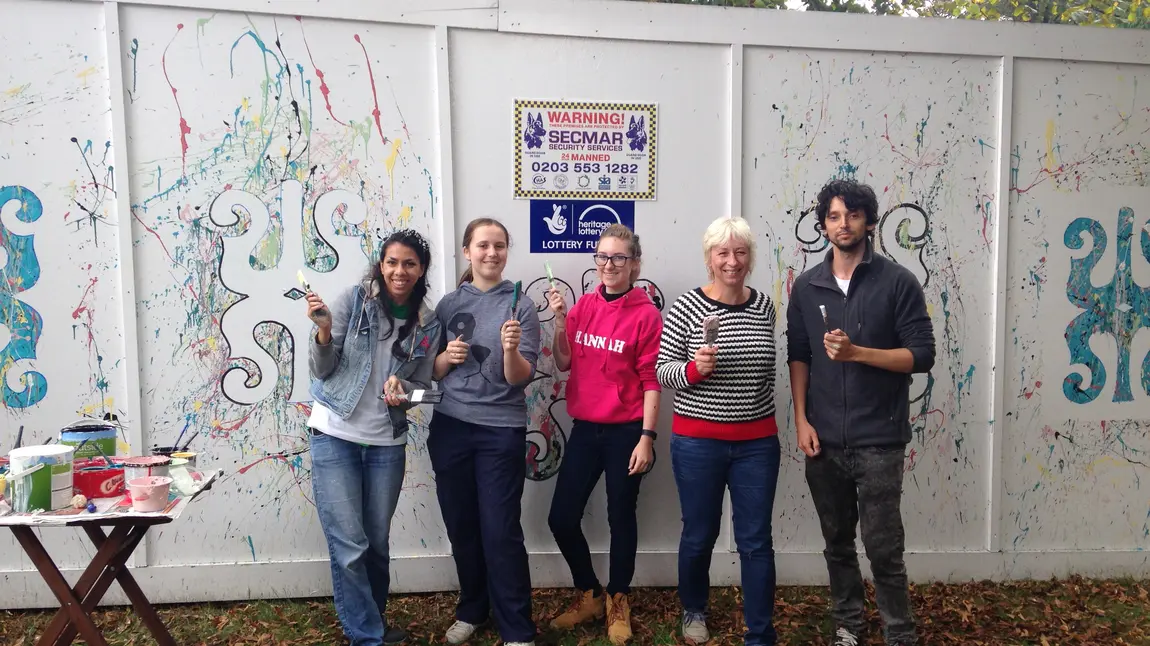 Five young volunteers with paintbrushes