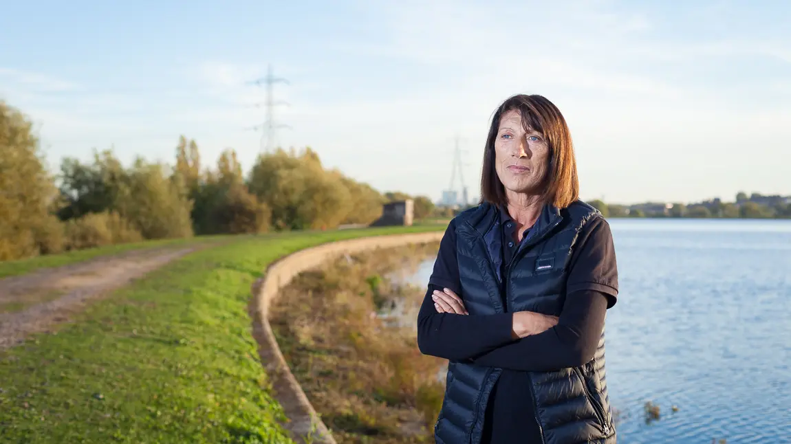A woman stands in front of a reservoir