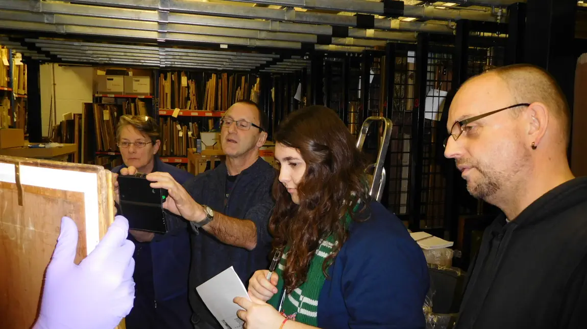 The team considers a painting for the exhibition in the picture store of Russell-Cotes 